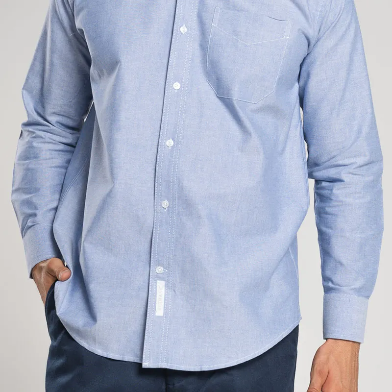 Detalle de camisas oxford azul clásica para hombre, con mano en el bolsillo, mostrando su tejido duradero y estilo atemporal