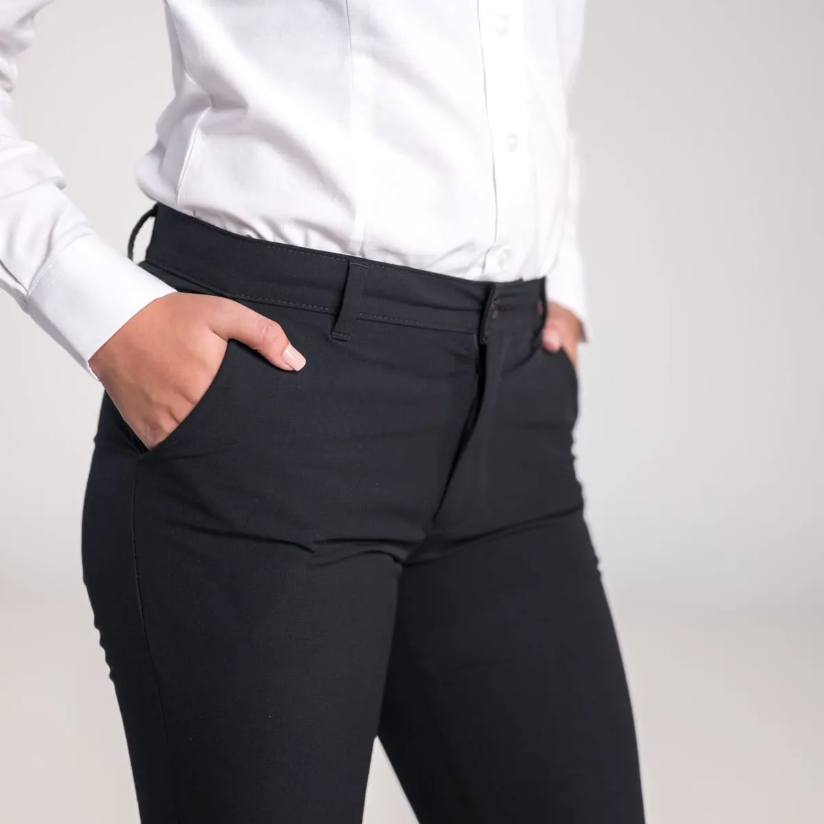 Detalle de mujer con pantalón negro de uniforme corporativo y manos en los bolsillos. Diseño funcional y moderno.