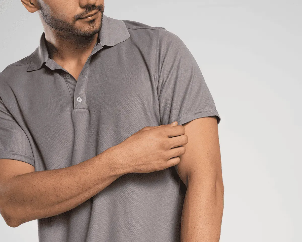 Foto de un hombre ajustando su polo gris de los uniformes corporativos de Airman